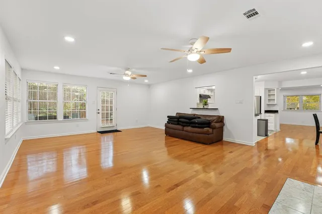 a large room with wooden floor chandelier a kitchen view and a window