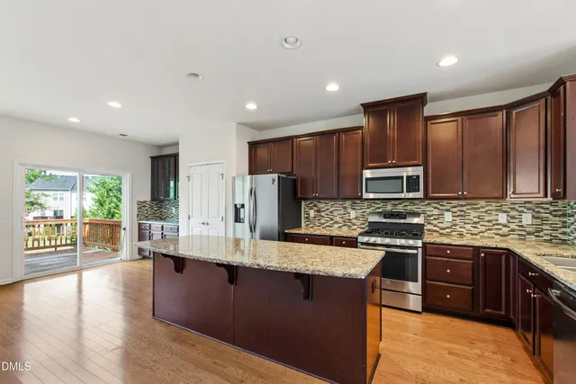 a kitchen with stainless steel appliances granite countertop a stove top oven a sink dishwasher a refrigerator and cabinets with wooden floor