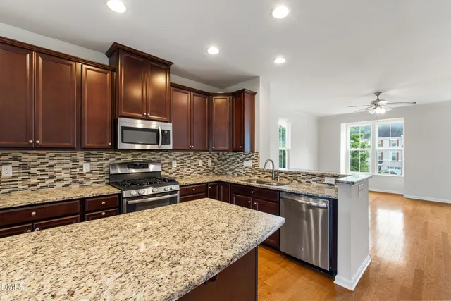 a kitchen with stainless steel appliances granite countertop wooden cabinets a stove top oven and granite counter tops