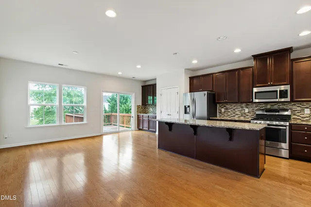 a kitchen with stainless steel appliances granite countertop a stove top oven a sink dishwasher a microwave oven and a refrigerator with wooden floor