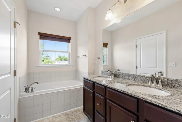 a bathroom with a granite countertop tub sink and mirror