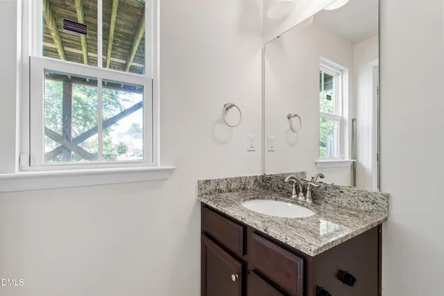 a bathroom with a granite countertop sink and a window
