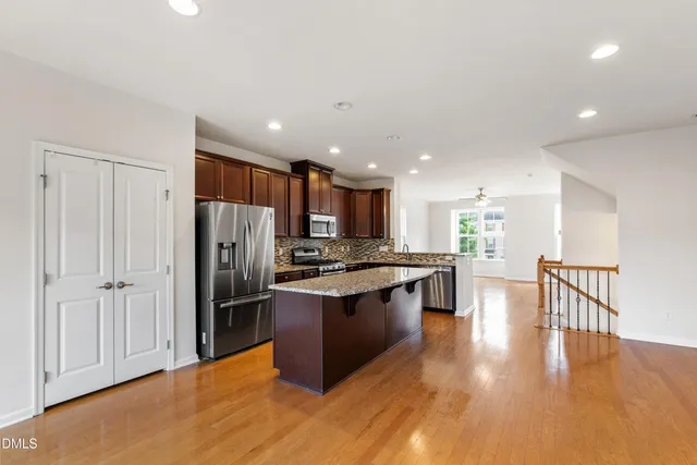 a kitchen with stainless steel appliances granite countertop a refrigerator a stove and a wooden floors
