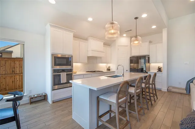a kitchen with stainless steel appliances kitchen island granite countertop a table chairs sink and cabinets