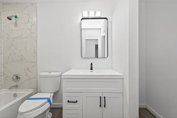 a bathroom with a toilet sink vanity tub and mirror