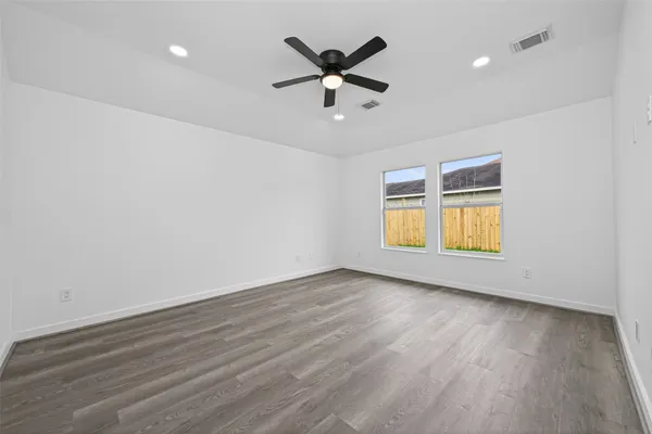 an empty room with wooden floor and ceiling fan