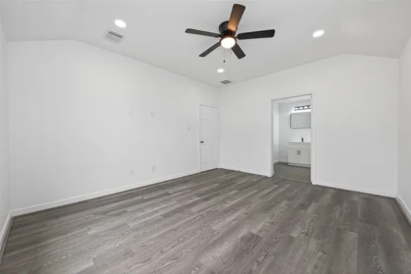 an empty room with wooden floor and ceiling fan