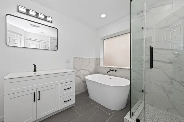 a bathroom with a white tub shower sink and mirror