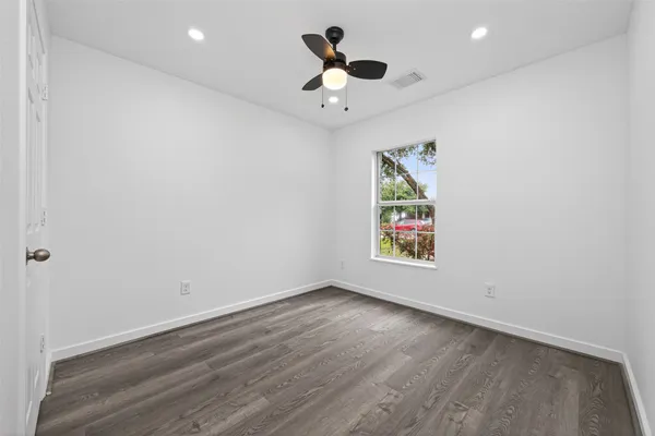 an empty room with ceiling fan and window