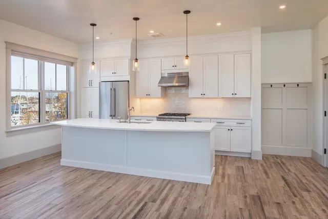 a large kitchen with cabinets wooden floor and a window