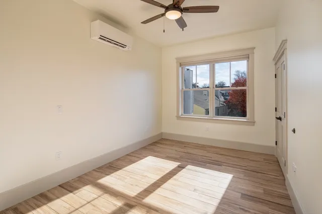 a view of an empty room with a window and wooden floor