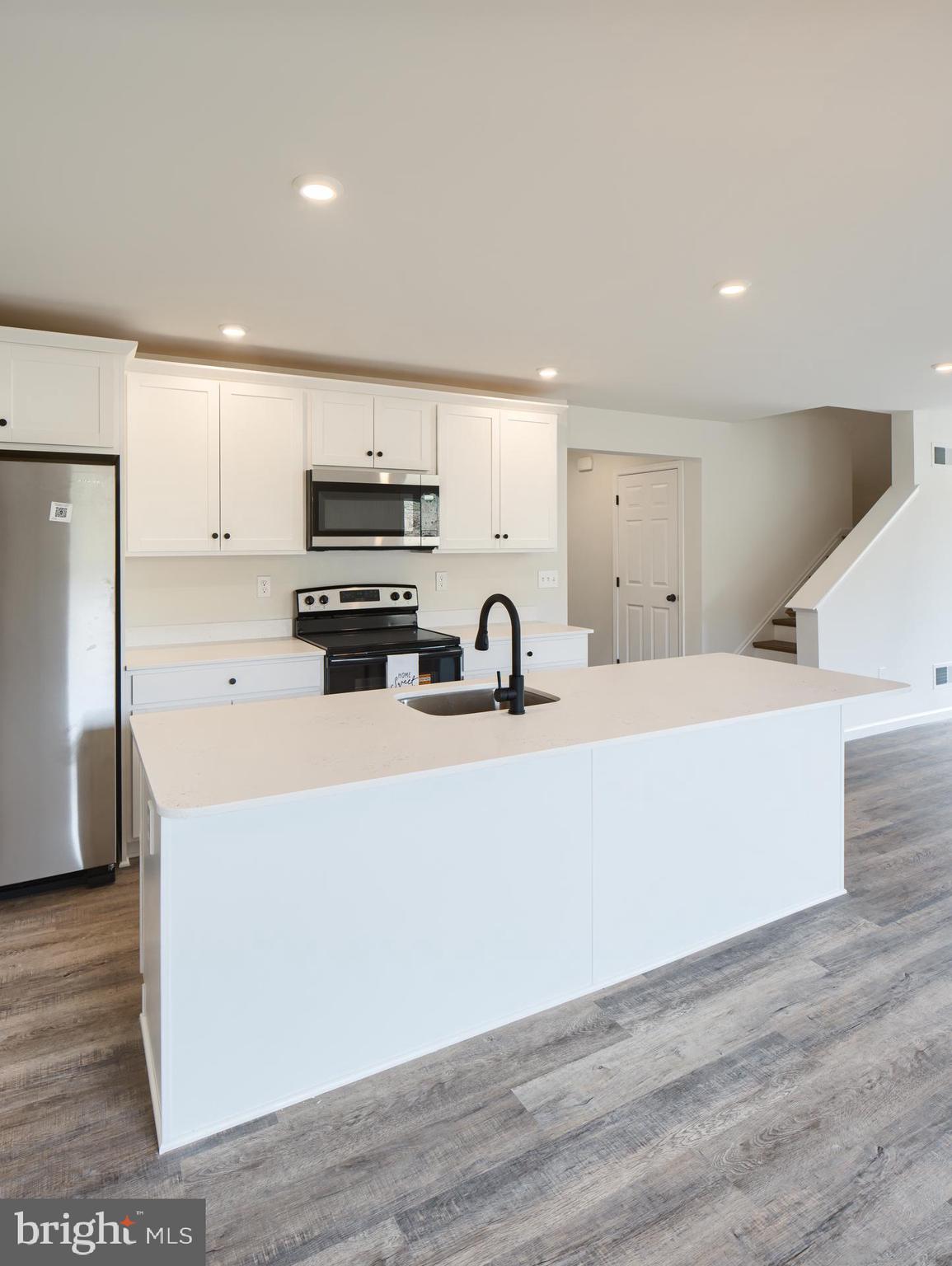 307 Boxwood Drive Windsor, PA 17366 - Photo 18 of 43 a kitchen with stainless steel appliances a stove a refrigerator a sink and white cabinets with wooden floor