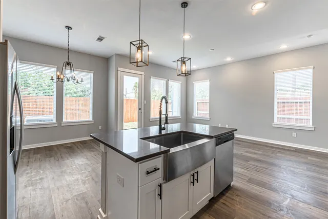 a kitchen with stainless steel appliances granite countertop a sink a window and wooden floor