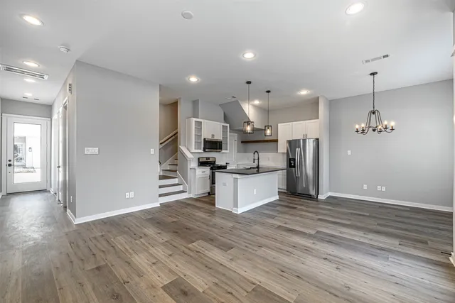 a large kitchen with stainless steel appliances kitchen island a large counter top and wooden floors