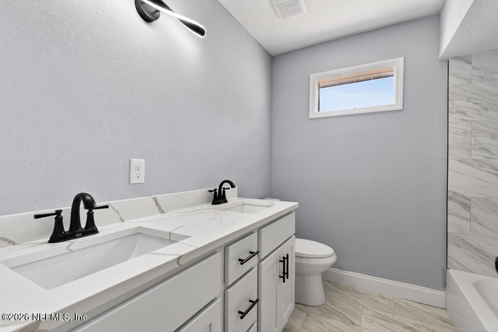 4040 Cove St Johns Road Jacksonville, FL 32277 - Photo 40 of 101 a bathroom with a sink a toilet and a mirror