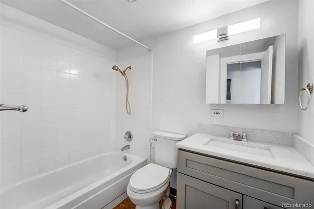 a bathroom with a granite countertop sink a toilet and shower