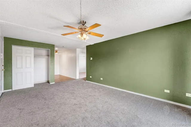 an empty room with a fan & a window