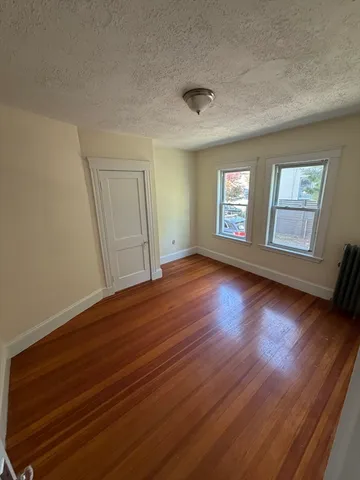 a view of empty room with window and wooden floor