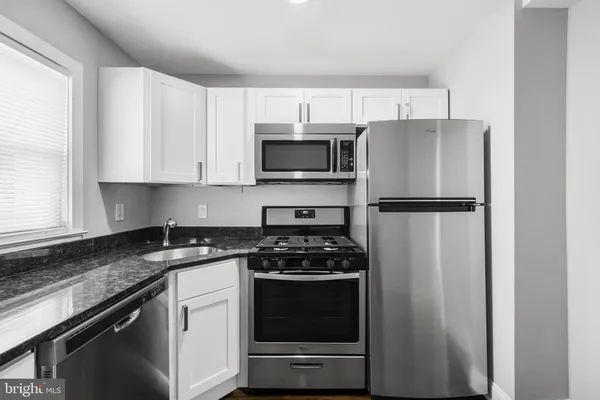 a kitchen with cabinets stainless steel appliances and a window