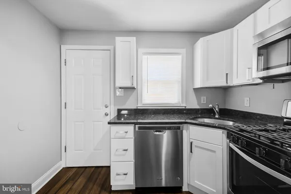 a kitchen with granite countertop white cabinets and black appliances