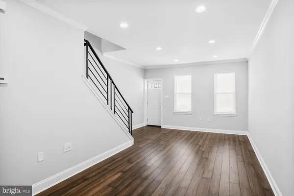 a view of an empty room with wooden floor and stairs