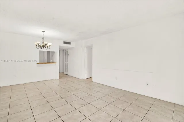 an empty room with kitchen and chandelier