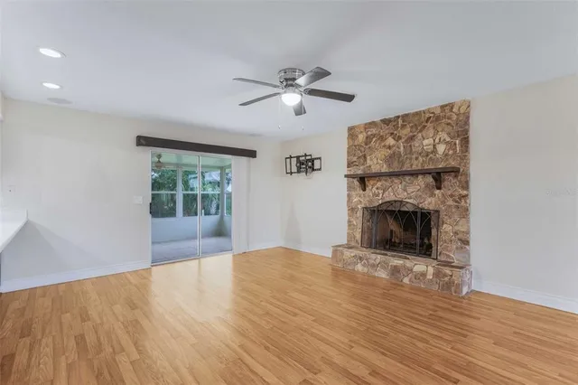 a view of an empty room with wooden floor fireplace and a window