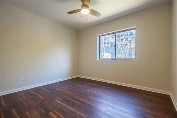 a view of an empty room with wooden floor and a window
