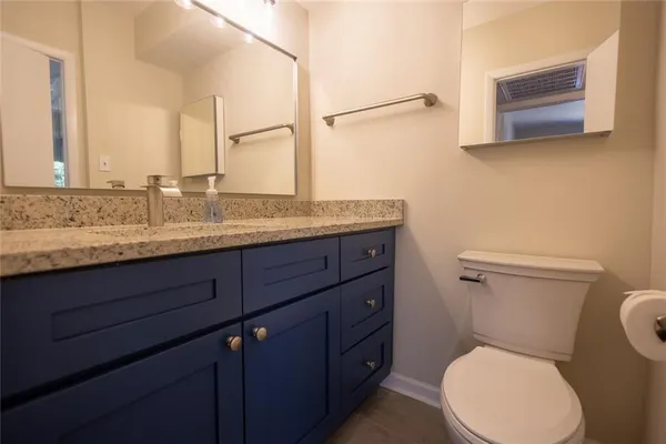 a bathroom with a granite countertop toilet sink and mirror