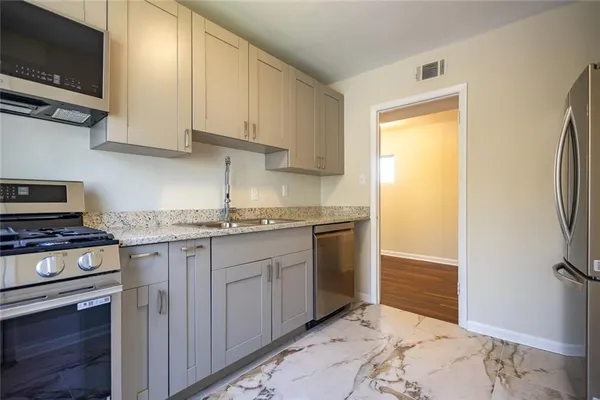 a kitchen with stainless steel appliances granite countertop a stove a sink and a refrigerator