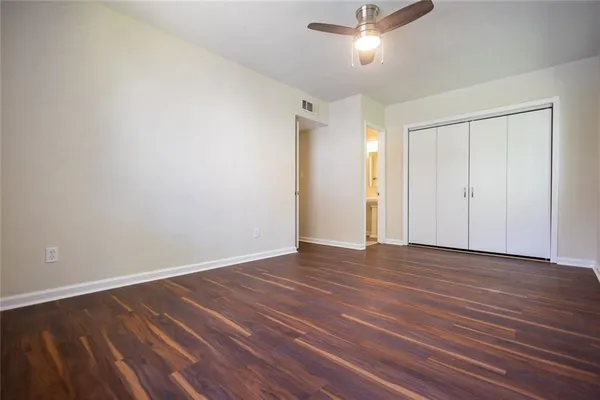 a view of an empty room with wooden floor and a ceiling fan