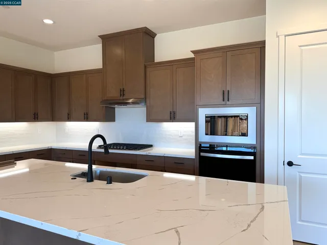 a kitchen with stainless steel appliances kitchen island granite countertop a refrigerator and a sink