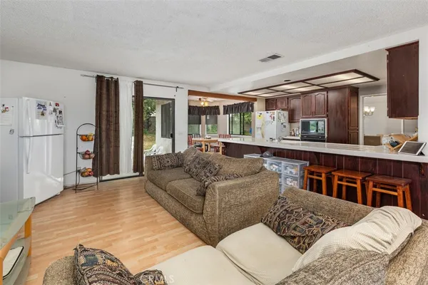 a living room with couches and large windows with kitchen view