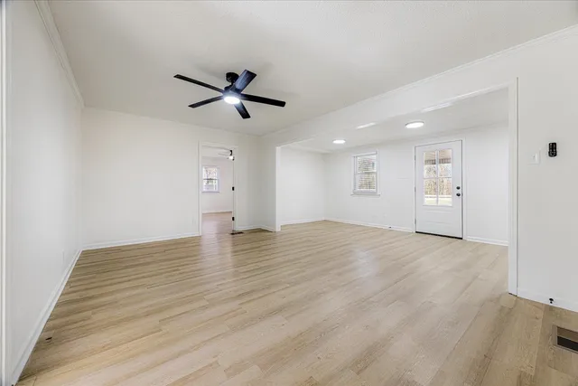 a view of empty room with wooden floor and ceiling fan
