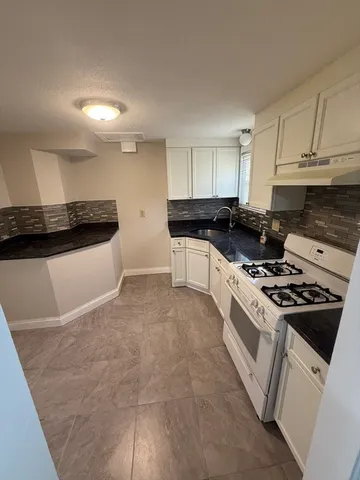 a kitchen with granite countertop a stove sink and cabinets