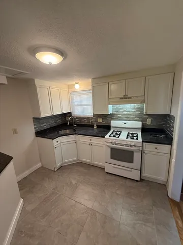 a kitchen with granite countertop white cabinets and white appliances