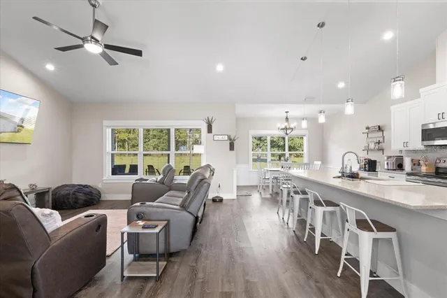 a living room with furniture a ceiling fan and a large window