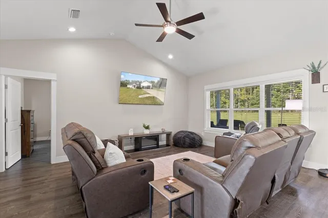 a living room with furniture ceiling fan and a large window