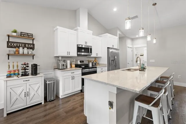 a kitchen with a sink a stove a refrigerator and white cabinets