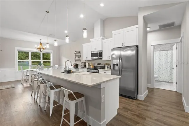 a kitchen with stainless steel appliances granite countertop a table chairs refrigerator and sink