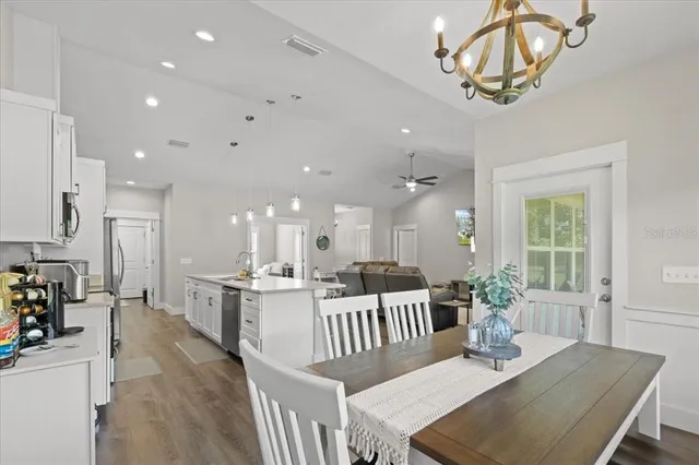 a view of a dining room and livingroom with furniture wooden floor a chandelier
