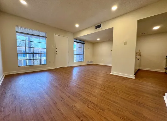 an empty room with wooden floor and windows