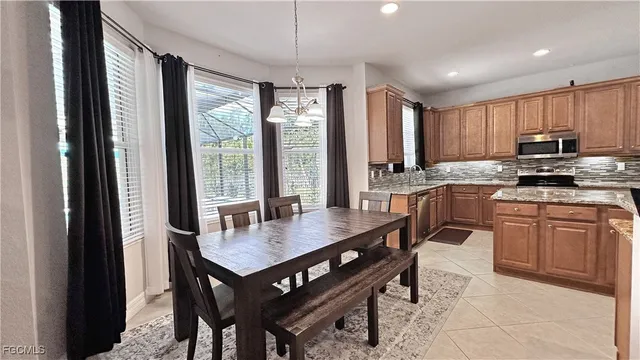 a kitchen with granite countertop a stove a sink dishwasher a dining table and chairs with wooden floor