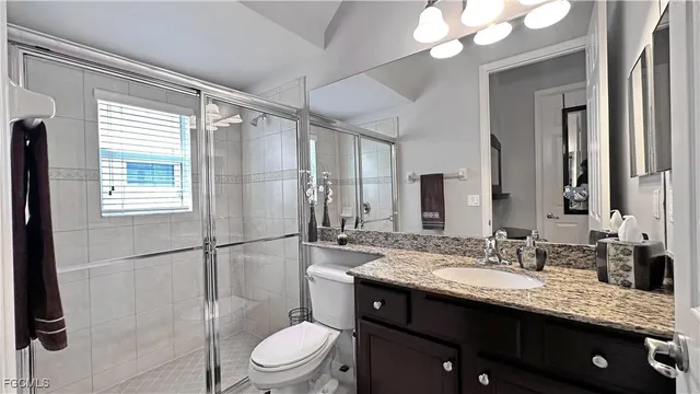 a bathroom with a granite countertop sink toilet a mirror and shower