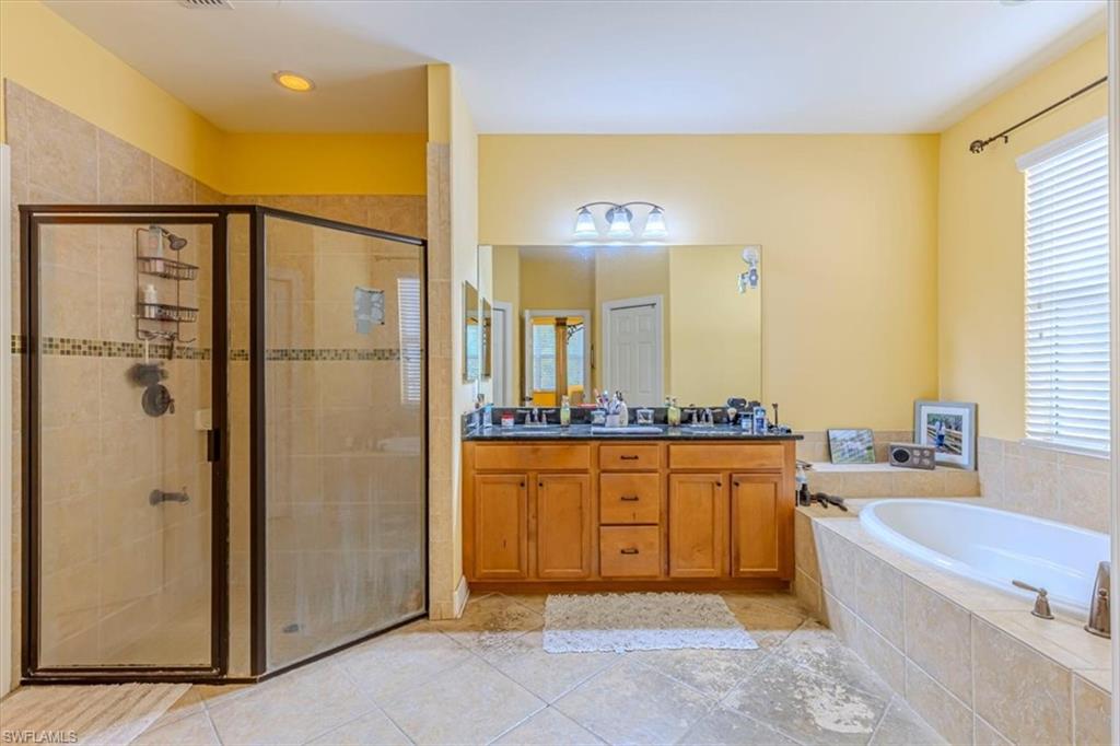 1674 Serrano Circle Naples, FL 34105 - Photo 16 of 21 Full bath featuring a garden tub, a shower stall, double vanity, and light tile patterned floors