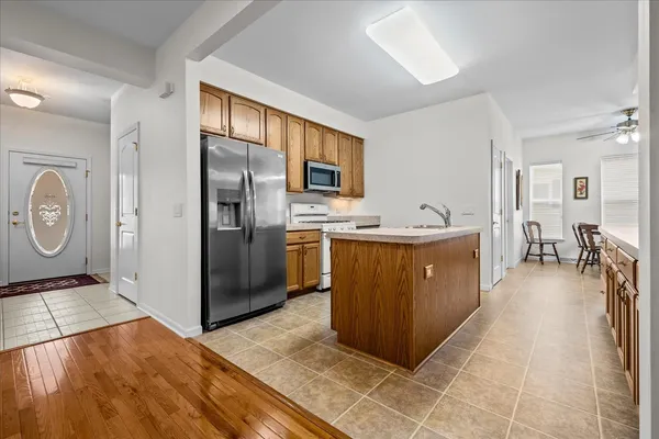 a kitchen with stainless steel appliances granite countertop a refrigerator a oven a sink dishwasher and wooden cabinets with wooden floor