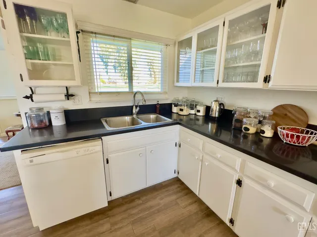 a kitchen with granite countertop a sink white cabinets and a window