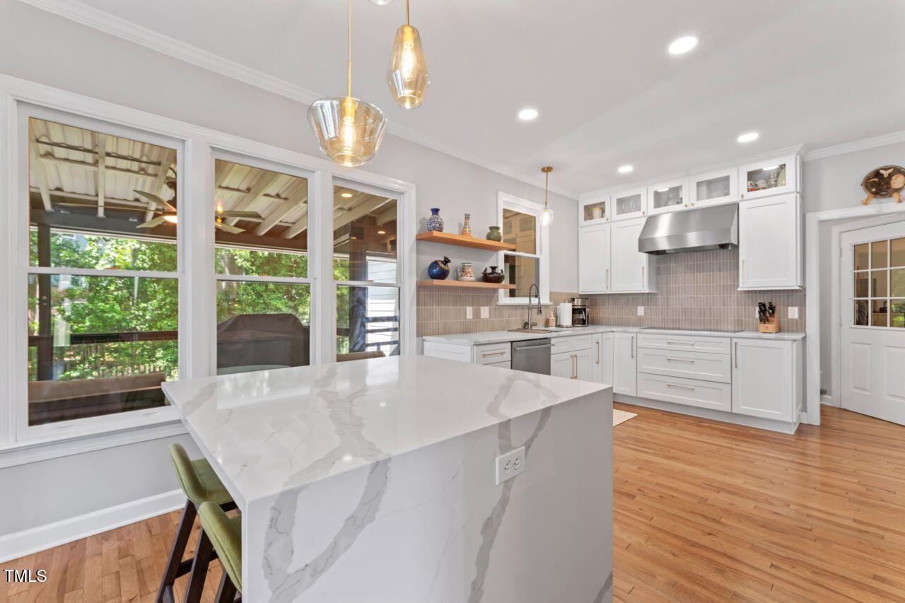 4408 Queenstown Court Raleigh, NC 27612 - Photo 18 of 49 a large kitchen with kitchen island a large window cabinets a sink and stainless steel appliances