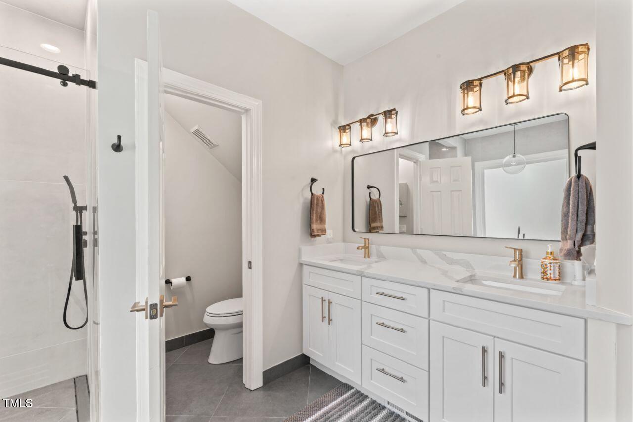 4408 Queenstown Court Raleigh, NC 27612 - Photo 25 of 49 a bathroom with a granite countertop sink a toilet and a mirror