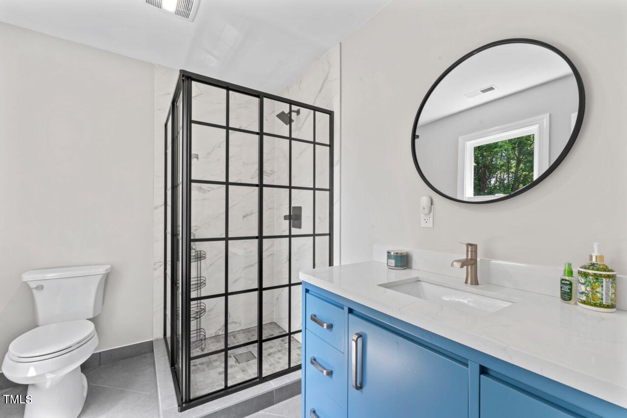 4408 Queenstown Court Raleigh, NC 27612 - Photo 37 of 49 a bathroom with a sink a mirror a toilet and a window